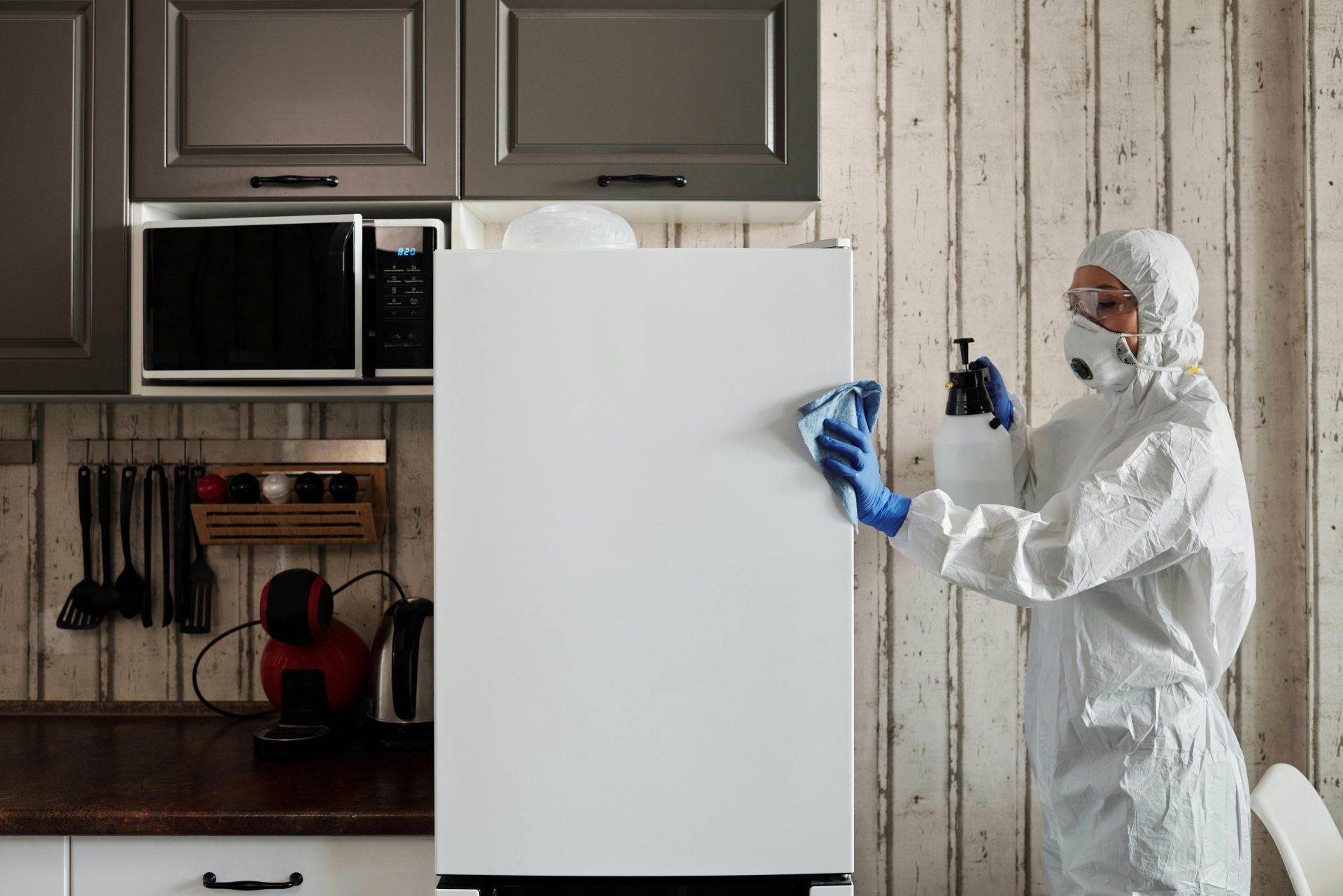 Eine Person in Schutzkleidung reinigt ein Küchengerät, um die Hygiene zu gewährleisten.