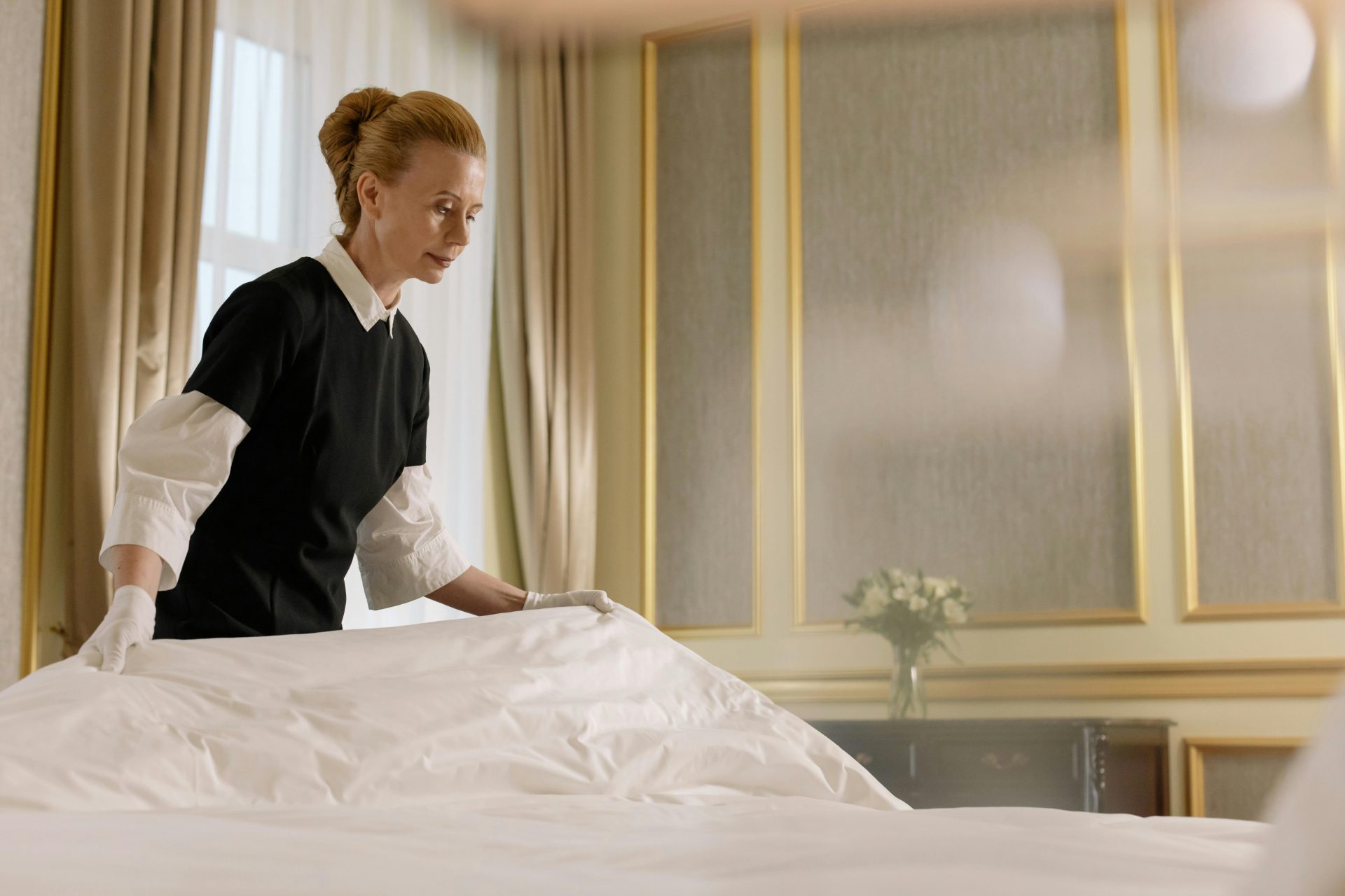 Eine professionelle Haushälterin repariert ein Bett in einem luxuriösen Hotelzimmer.